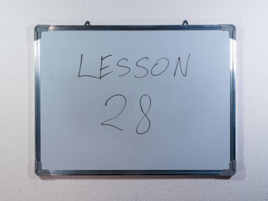 Eğitim içeriğini, öğrenim yapısını ve öğretim yöntemini temsil eden temiz beyaz duvar arkaplanı üzerine LESSON kavramını gösteren beyaz tahta