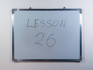 Eğitim içeriğini, öğrenim yapısını ve öğretim yöntemini temsil eden temiz beyaz duvar arkaplanı üzerine LESSON kavramını gösteren beyaz tahta