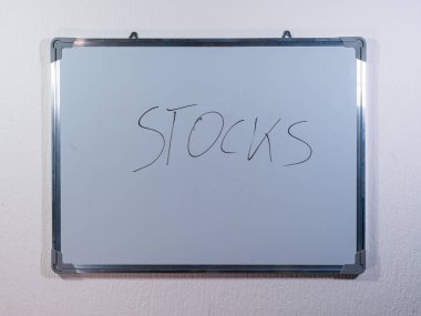 Borsa, yatırım ve finansal varlıkları temsil eden temiz beyaz duvar arkaplanı üzerine STOCKS kavramını gösteren Whiteboard