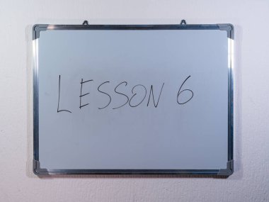 Eğitim, öğrenme ve öğretim sürecini temsil eden temiz beyaz duvar arkaplanı hakkında LESSON kavramını gösteren beyaz tahta