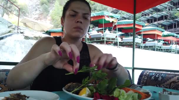 山の川の上の小さな滝で水の上のレストランで食事をする女の子 — ストック動画