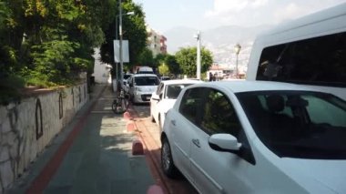 17 Eylül 2020, ALANA, TURKEY: Alanya şehir merkezindeki butiklerin, dükkanların ve kafelerin önünden geçen park edilmiş araçlar boyunca cadde boyunca yürüyor.