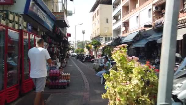 17 SEPTEMBER 2020, ALANYA, TURKEY: Wandelen langs de straat langs de geparkeerde auto 's langs boetieks, winkels en cafés in het centrum van Alanya stad. — Stockvideo