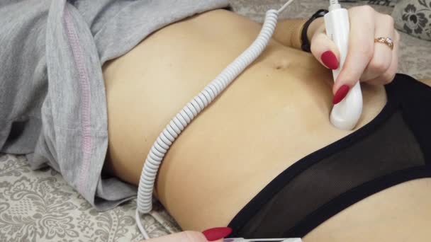 Беременная женщина крупным планом слушает звук сердца плода через карманный доплер на кровати — стоковое видео