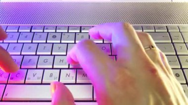 First-person view, hands type text on laptop keyboard