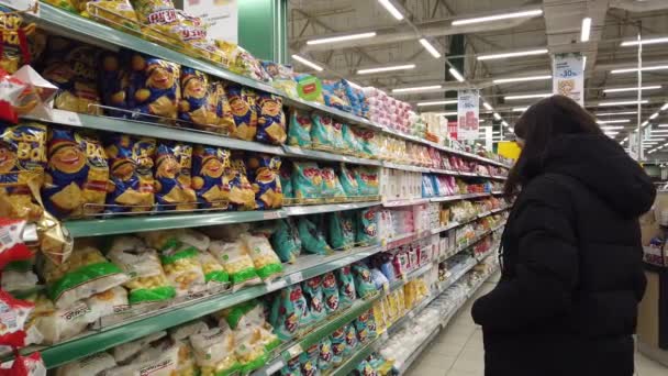 2020年12月10日 俄克拉荷马州莫斯科市 一位女士站在货架旁边 她的货架上摆放着一些商品 想在超市里挑选一种商品 — 图库视频影像