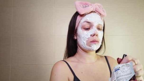 Ung Brunett Med Rosa Pannband Som Applicerar Alginatmask Ansiktet Med — Stockvideo