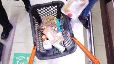 Süpermarket alışverişçileri market alışverişini el arabasına koyarlar.