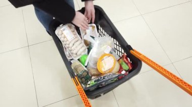 Süpermarket alışverişçileri market alışverişini el arabasına koyarlar.