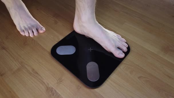 Чоловік перевіряє свою вагу. Ноги на вагах . — стокове відео