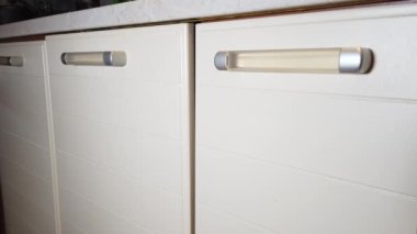 Adam mutfak dolabında bir çekmece açıyor.