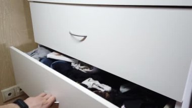 Adam kabinede bir çekmece açıyor.