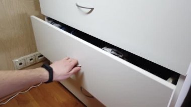 Adam kabinede bir çekmece açıyor.