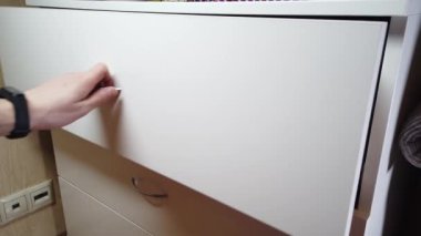 Adam kabinede bir çekmece açıyor.