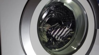 Çamaşırları çamaşır makinesinde yıkamak. Dönen çamaşır makinesi davulunun videosunu kapat.