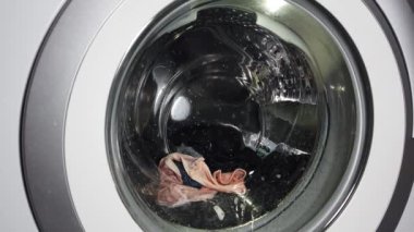 Çamaşırları çamaşır makinesinde yıkamak. Dönen çamaşır makinesi davulunun videosunu kapat.