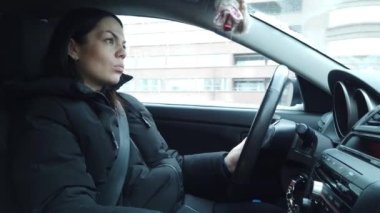 Kadın portresi, yan görüş. Kadın sürücü yolda. Genç bir kadın şehirde direksiyonda el ele tutuşarak araba kullanıyor..