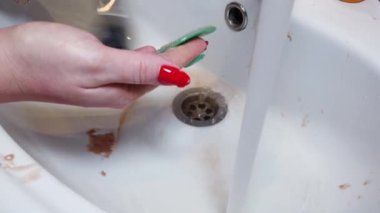 Kapalı kadın makyaj fırçalarını musluk suyuyla yıkıyor.