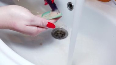 Kadınlar makyaj fırçalarını musluk suyuyla yıkıyor.