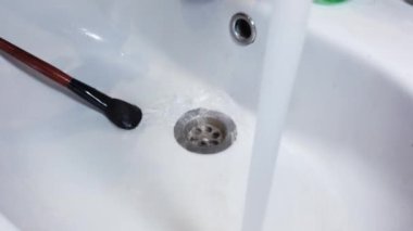 Kadınlar makyaj fırçalarını musluk suyuyla yıkıyor.