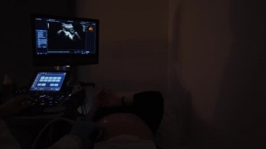 Doktor hamile bir kızla ultrason yapıyor.