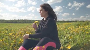 Kız çiçek açan karahindibalarla kaplanmış bir çayırda oturuyor. Bir kadın portresi bir buket sarı çiçek seçer. Bir tarlada karahindiba çiçeği..