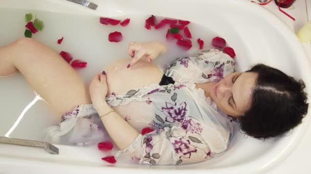 İç çamaşırlı hamile kız süt ve gül yapraklarıyla banyo yapıyor. — Stok video