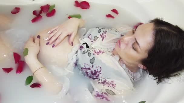 속옷 차림의 임신 한 여자가 우유와 장미꽃 잎으로 목욕을 한다 — 비디오