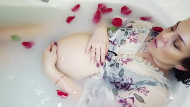 İç çamaşırlı hamile kız süt ve gül yapraklarıyla banyo yapıyor. — Stok video