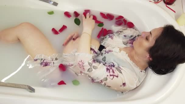 속옷 차림의 임신 한 여자가 우유와 장미꽃 잎으로 목욕을 한다 — 비디오