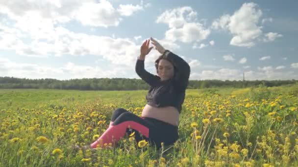 Une fille enceinte se repose dans un champ avec de belles fleurs jaunes — Video