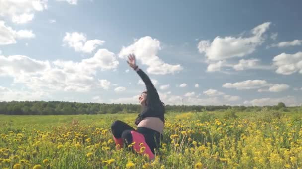 Une fille enceinte se repose dans un champ avec de belles fleurs jaunes — Video