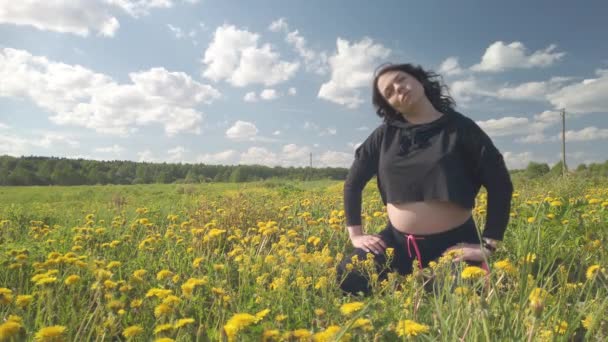 En gravid pige hviler på en mark med smukke gule blomster – Stock-video
