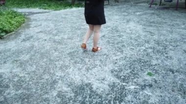 Kavak kabarıklığının biriktiği asfaltta yürüyen bir kızın bacaklarını kapatın.