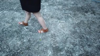 Kavak kabarıklığının biriktiği asfaltta yürüyen bir kızın bacaklarını kapatın.