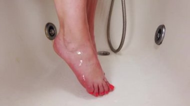 Kadın banyoda ellerini yıkıyor. Bacaklara ovalama uyguluyor..