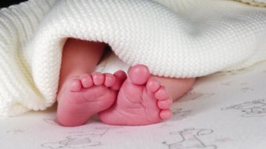 Bebek bezi içinde sırt üstü uzanmış, küçük bacaklarını sıvazlarken yakın plan çekimler.