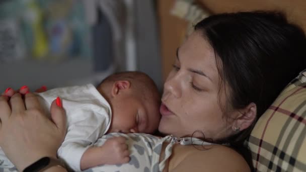 婴儿躺在母亲的胸前 母亲和孩子在家里躺在床上休息 — 图库视频影像