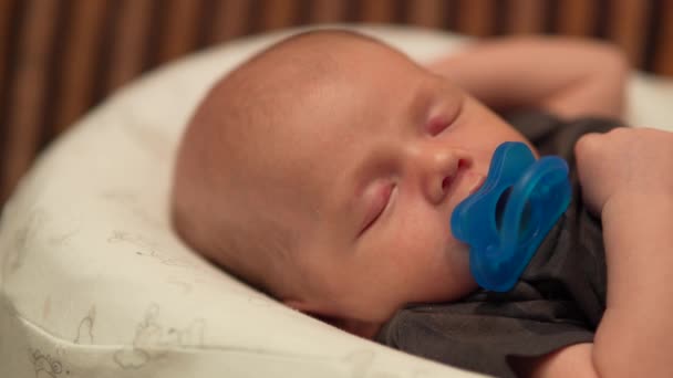 Cute pretty little baby boy sleeping with a pacifier on white cocoon. — Stock Video