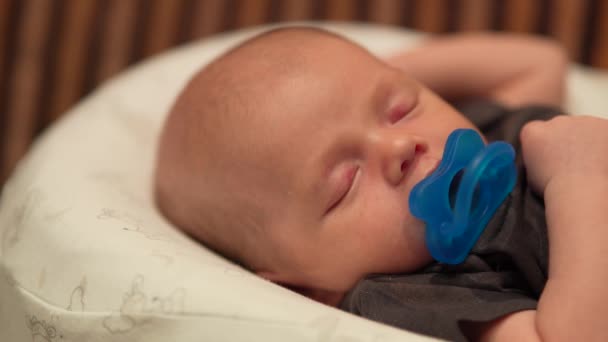 Cute pretty little baby boy sleeping with a pacifier on white cocoon. — Stock Video