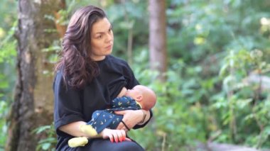 Kadın ormanda dinlenirken bebeğini emziriyor..