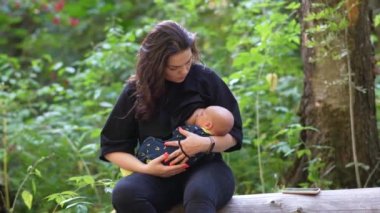 Kadın ormanda dinlenirken bebeğini emziriyor..