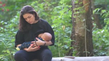 Kadın ormanda dinlenirken bebeğini emziriyor..