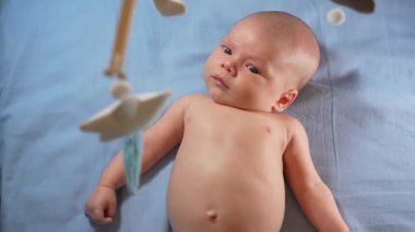 Çocuk, bebek beşiğinin üzerinde dönen el yapımı yumuşak oyuncaklarla müzikal bebek hareketine bakıyor..