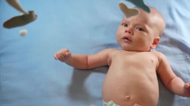 Çocuk, bebek beşiğinin üzerinde dönen el yapımı yumuşak oyuncaklarla müzikal bebek hareketine bakıyor..