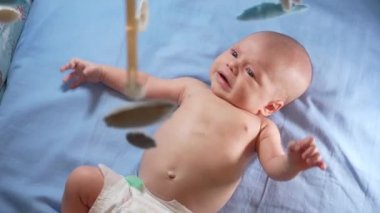 Çocuk, bebek beşiğinin üzerinde dönen el yapımı yumuşak oyuncaklarla müzikal bebek hareketine bakıyor..