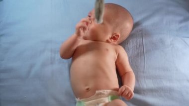 Çocuk, bebek beşiğinin üzerinde dönen el yapımı yumuşak oyuncaklarla müzikal bebek hareketine bakıyor..