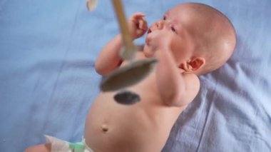 Çocuk, bebek beşiğinin üzerinde dönen el yapımı yumuşak oyuncaklarla müzikal bebek hareketine bakıyor..