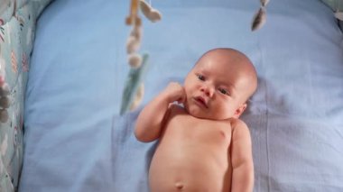 Çocuk, bebek beşiğinin üzerinde dönen el yapımı yumuşak oyuncaklarla müzikal bebek hareketine bakıyor..