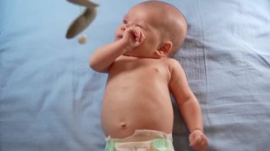 Çocuk, bebek beşiğinin üzerinde dönen el yapımı yumuşak oyuncaklarla müzikal bebek hareketine bakıyor..